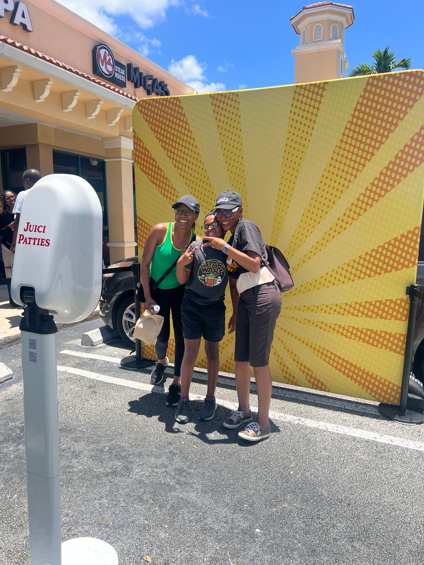 Family posing in front of the custom Juici Patties sunburst backdrop