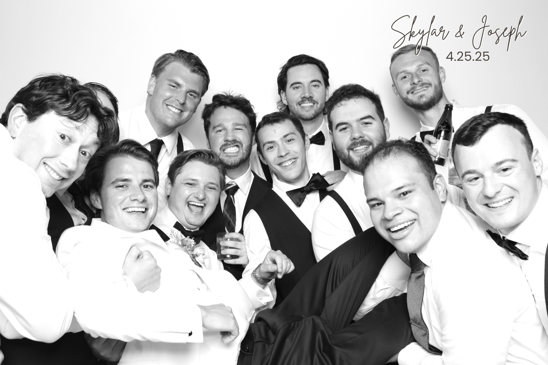 Large group of guests in formal attire crowds together smiling in a playful black-and-white portrait.