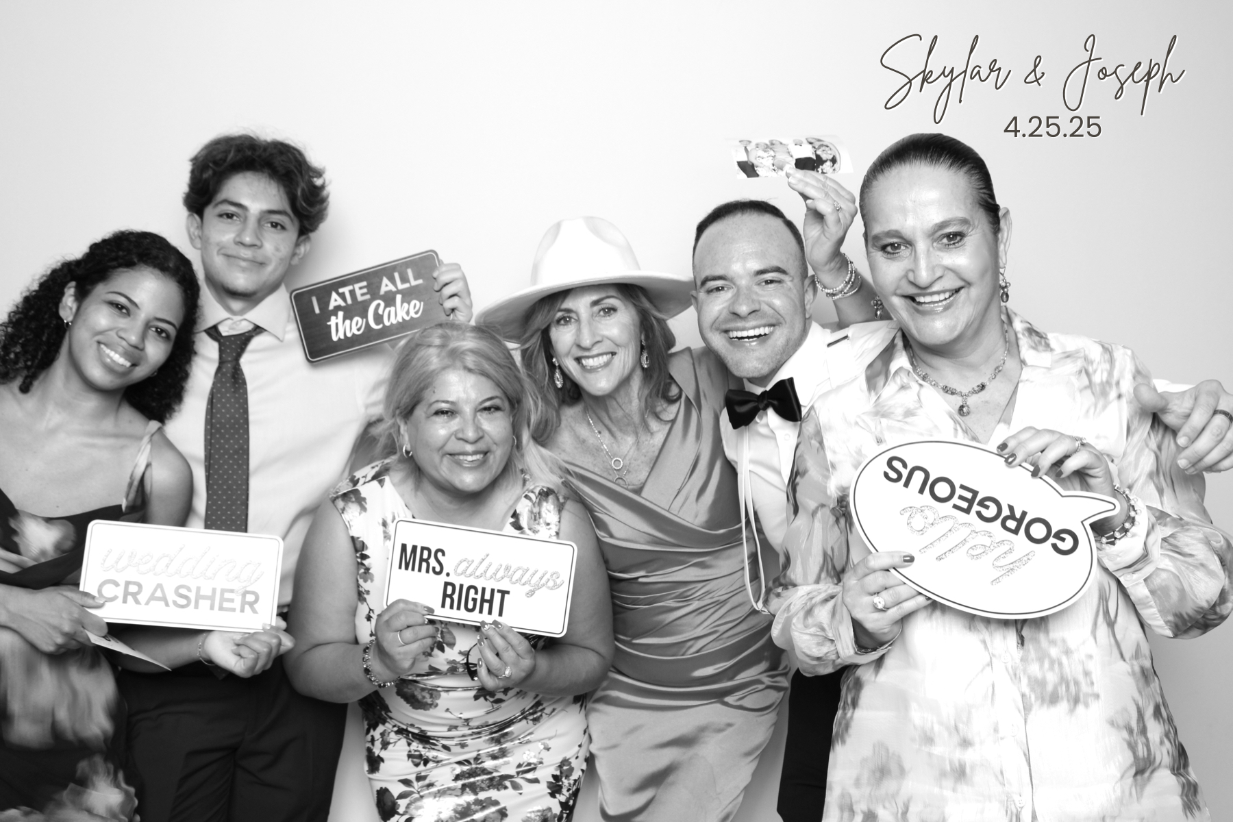Group of wedding guests crowds together holding playful celebration signs.