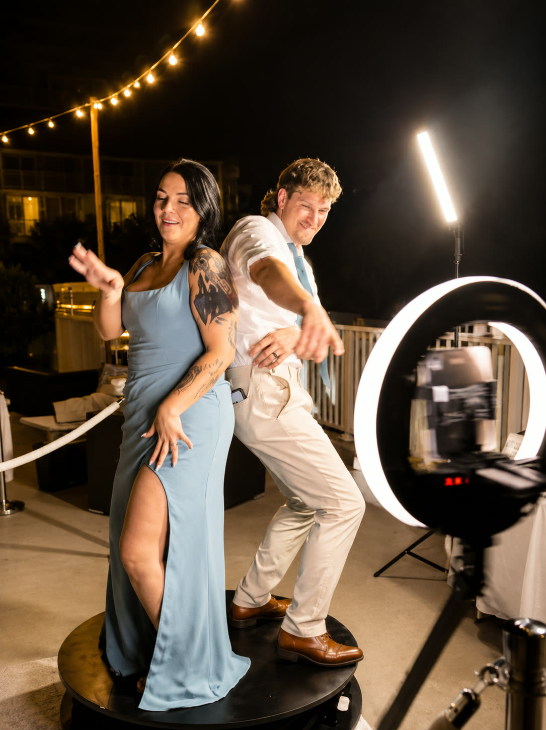 A couple dancing on the 360 video booth platform under string lights