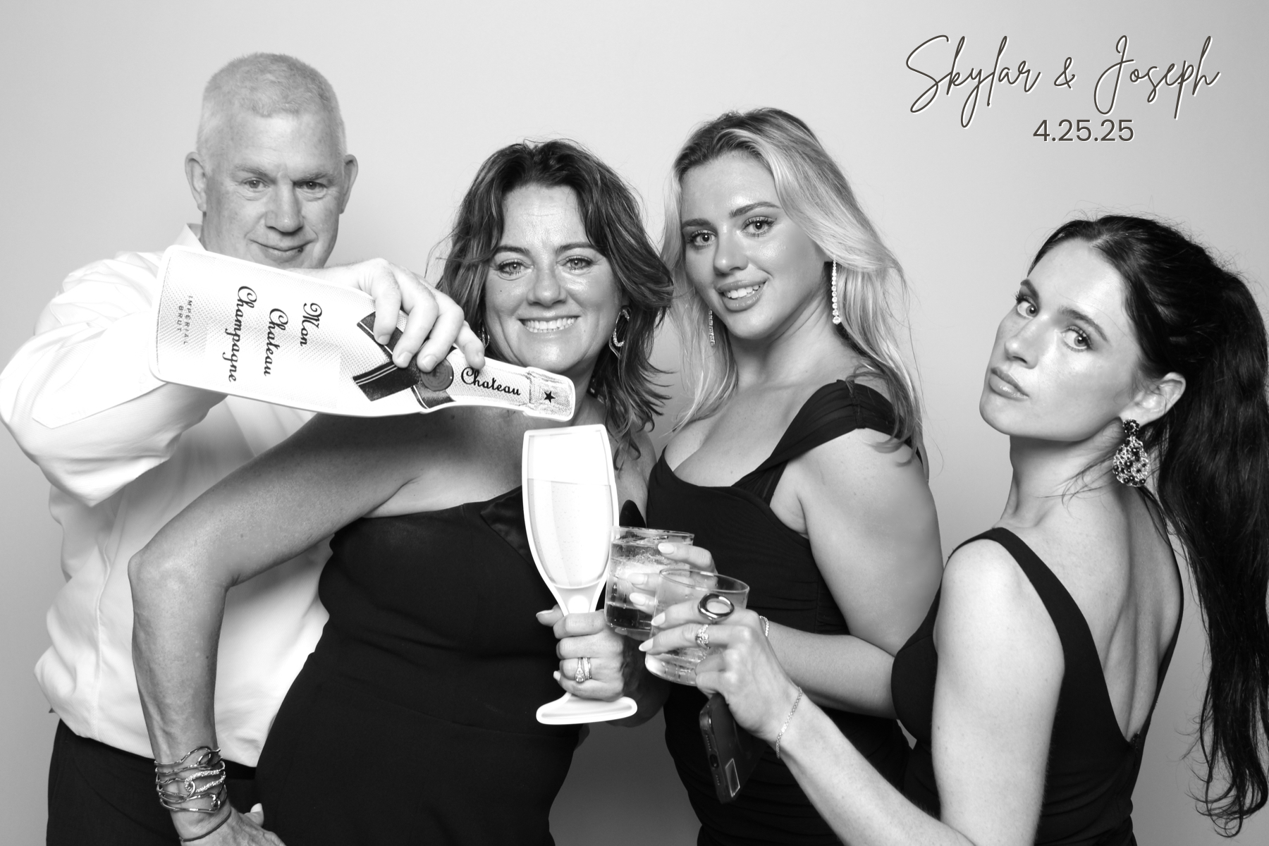 Four guests in formalwear pose with drinks and playful expressions.