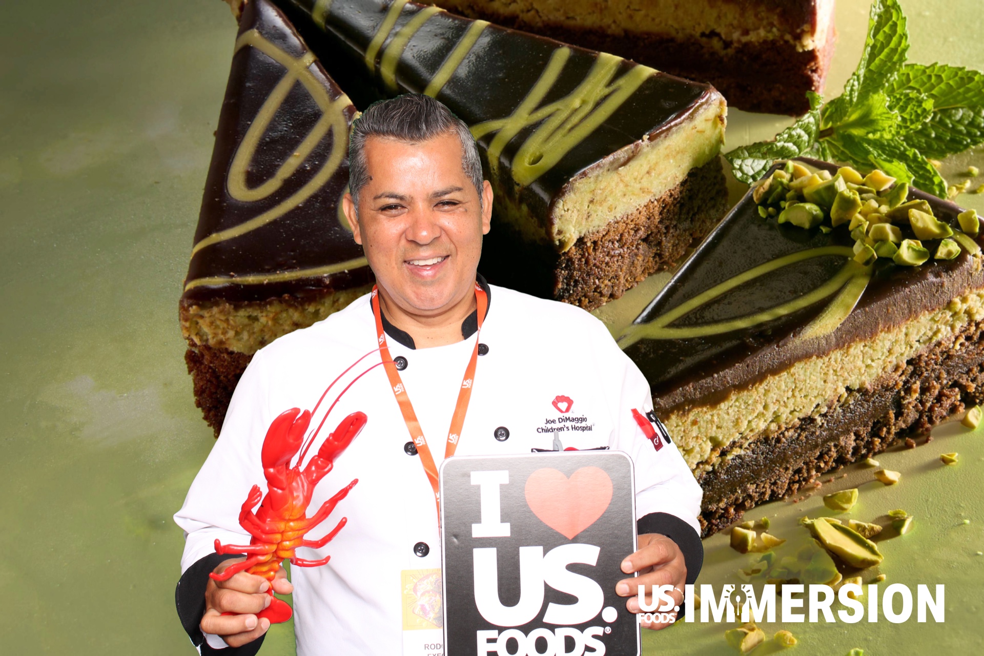 Chef holding an I Love US Foods sign in front of a pistachio dessert green screen backdrop