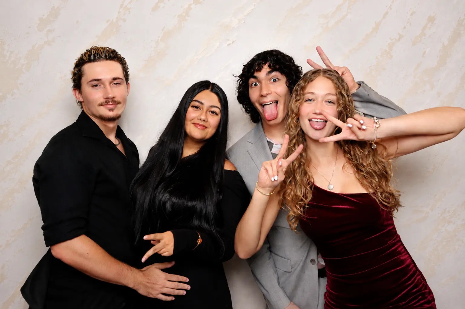 Group of four friends laughing and posing in the photo booth