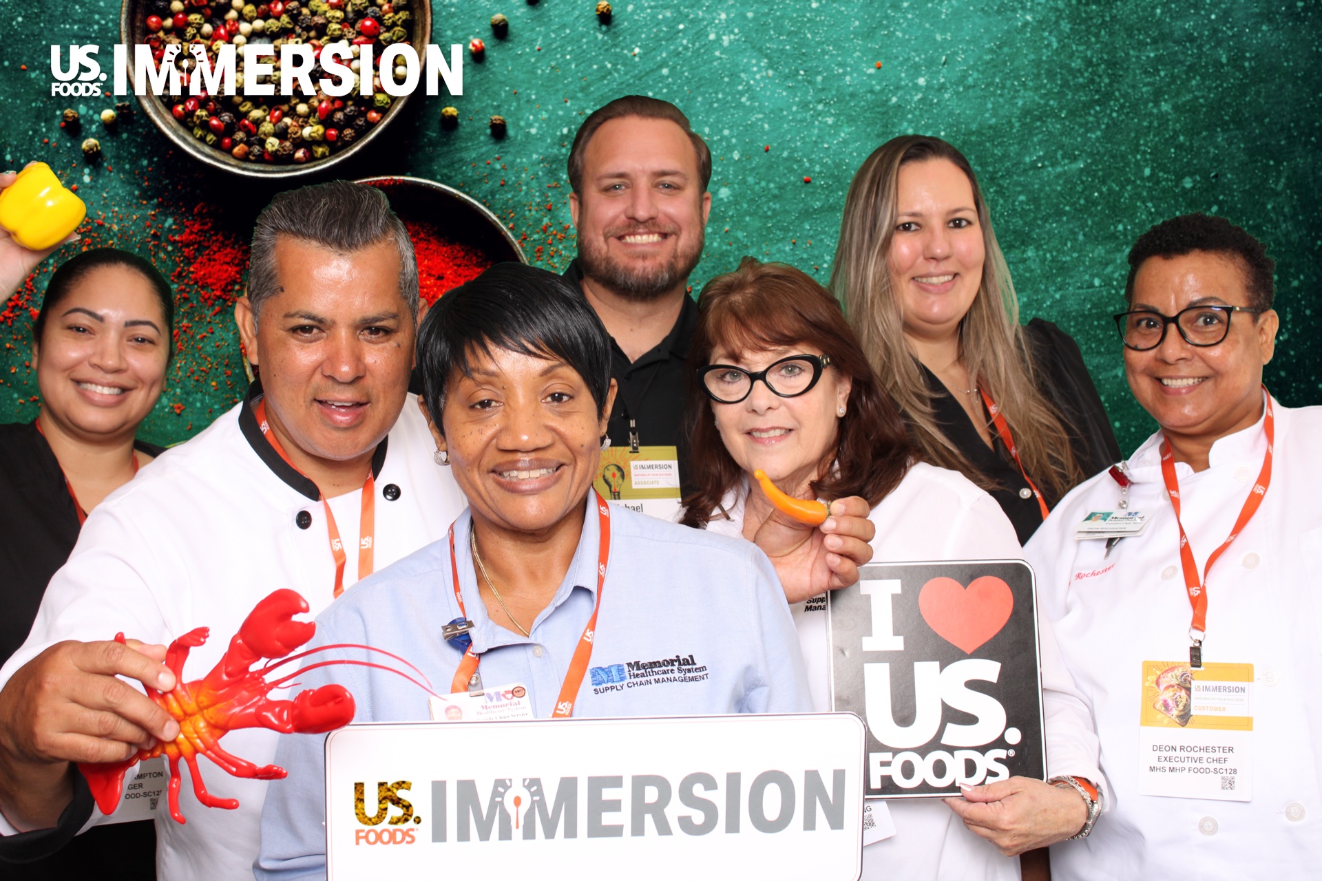 Group of US Foods Immersion attendees posing with branded props on a spice backdrop