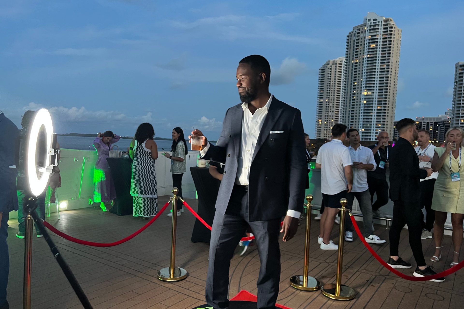 Guest walking the red carpet at a Miami rooftop event with a 360 video booth and ring light