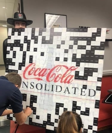 Employees adding tiles to a Coca-Cola Consolidated logo photo mosaic