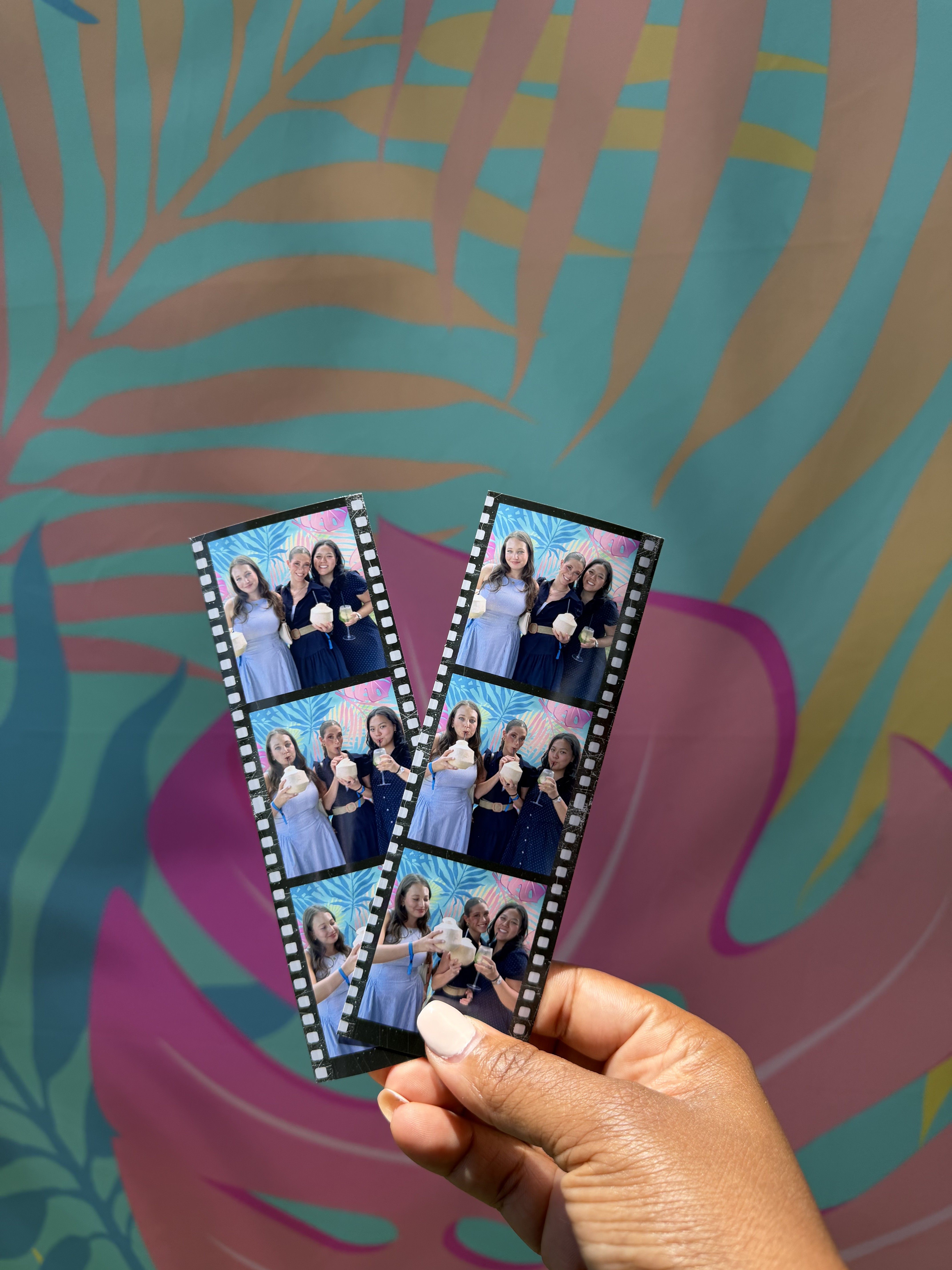Printed photo strips held in front of the tropical backdrop