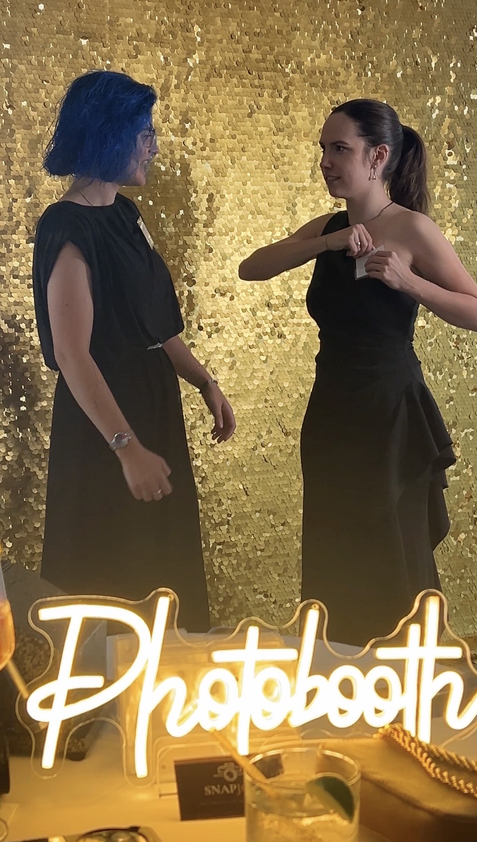 Neon Photobooth sign and gold sequin backdrop set up at the Liberty and Leadership Gala