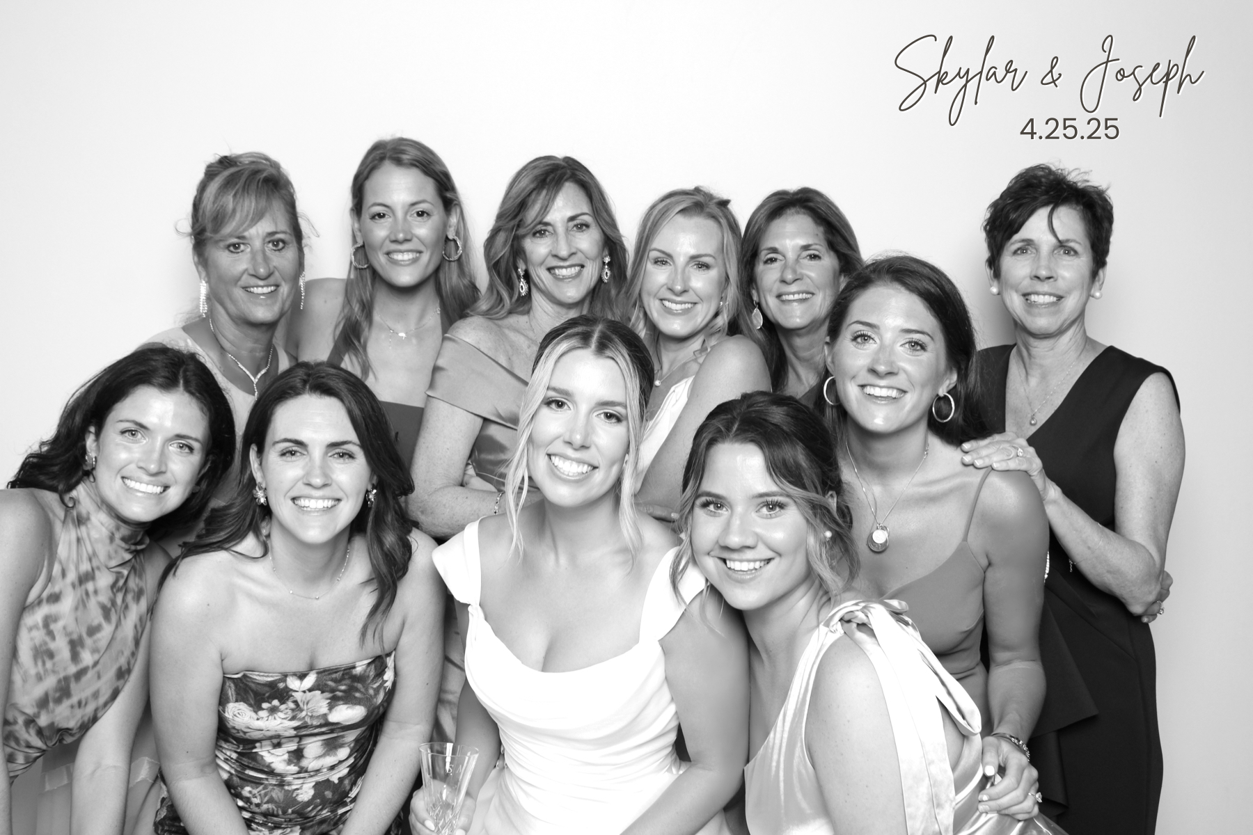 Large group of women in formal attire smiles together in a polished black-and-white portrait.