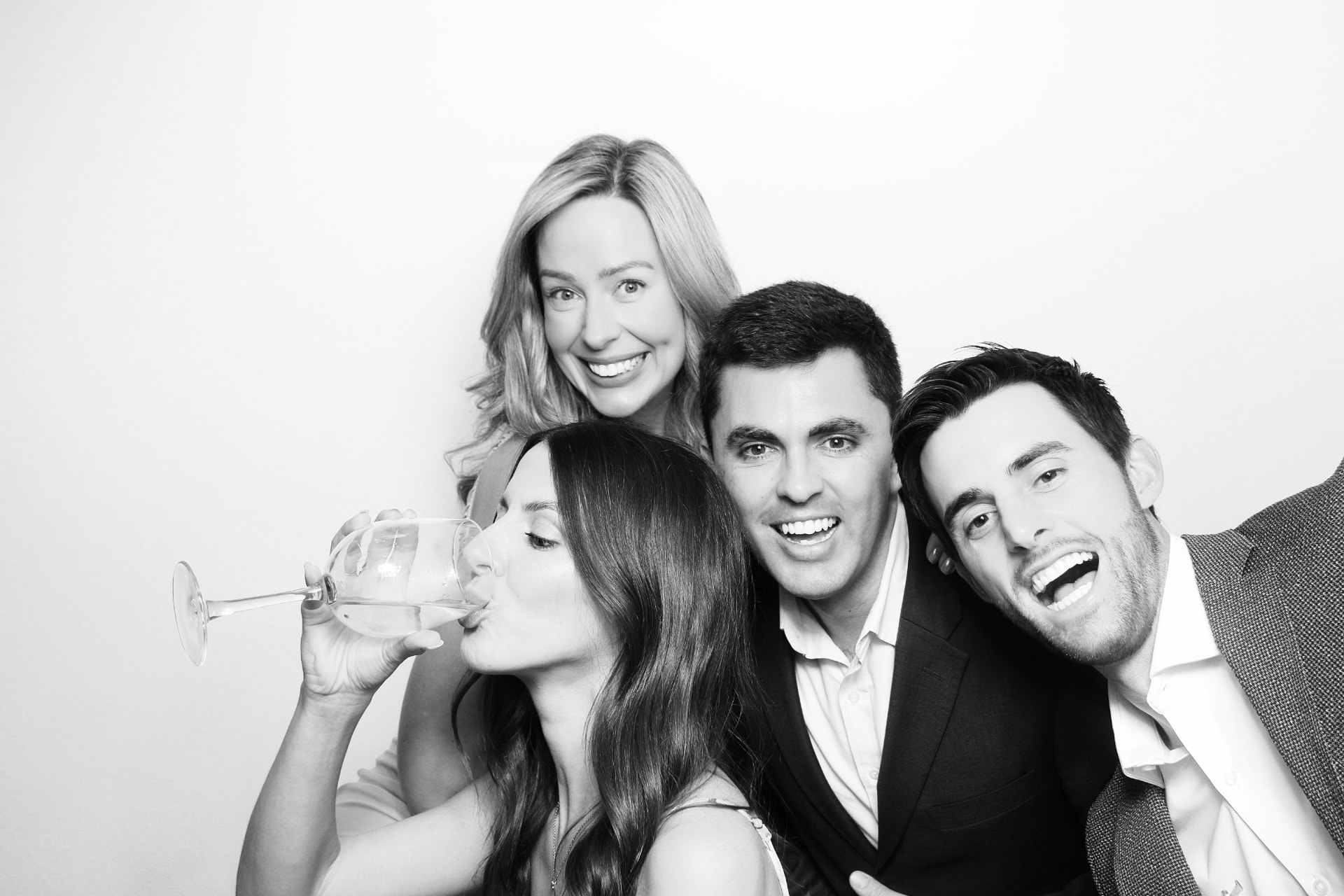 Four wedding guests laughing together in a black-and-white portrait