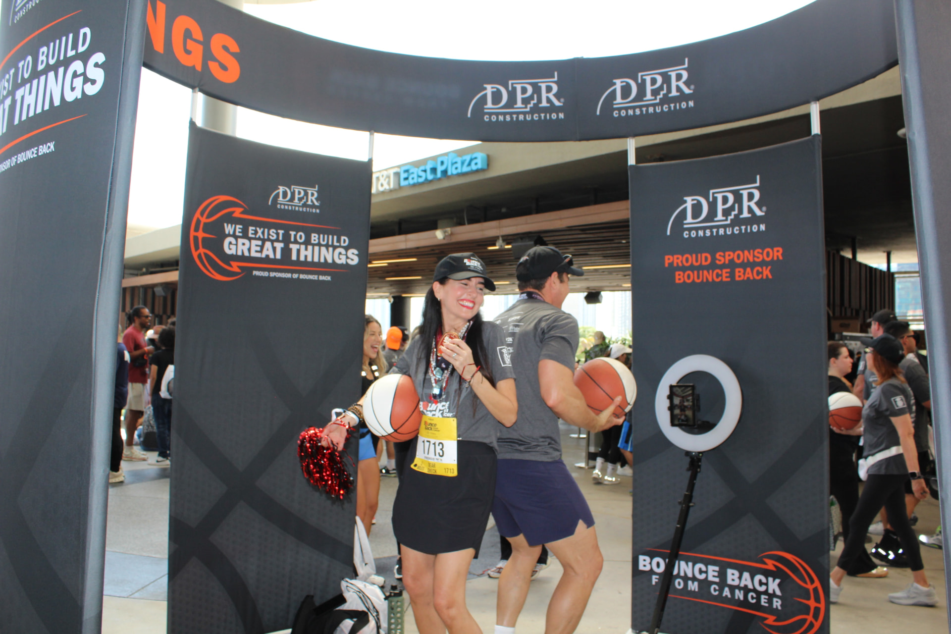 Runners with race bibs and medals celebrating inside the 360 Pavilion at the Kaseya Center