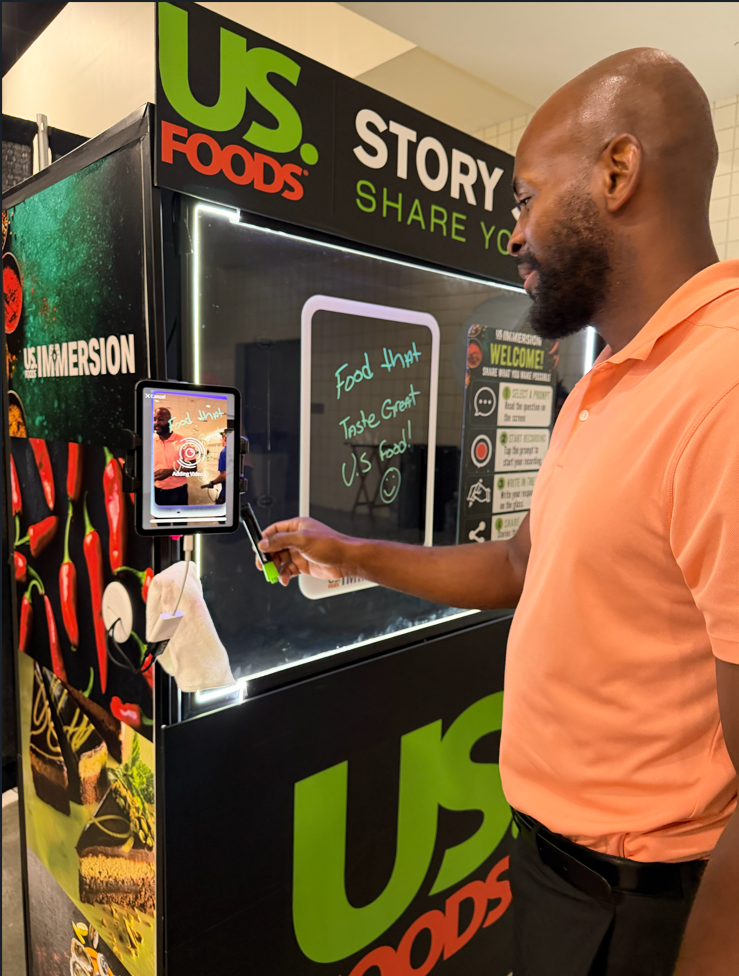 Attendee writing Food that tastes great on the Story Studio glass while recording a message
