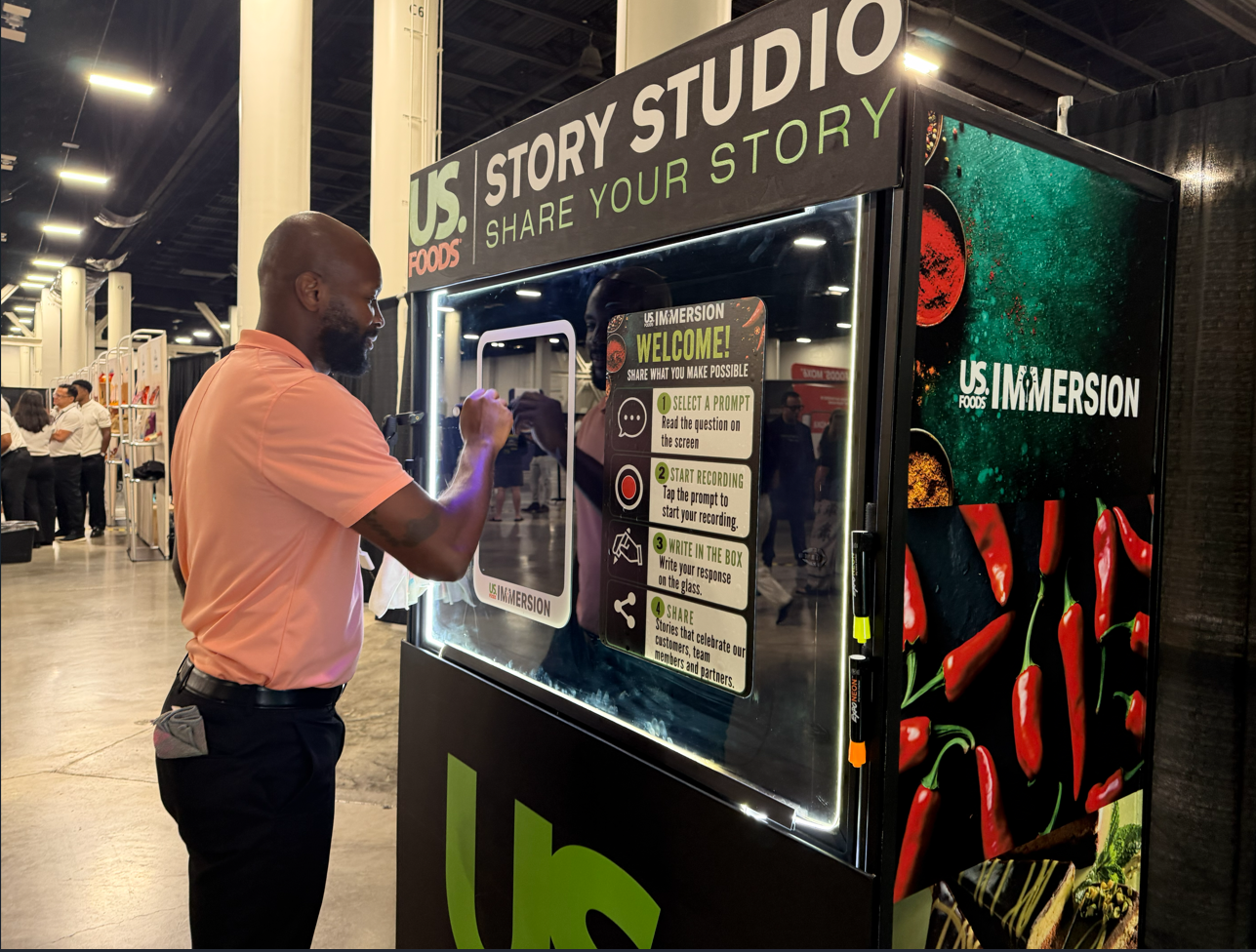 Guest writing on the glass of the custom-branded US Foods Story Studio message booth