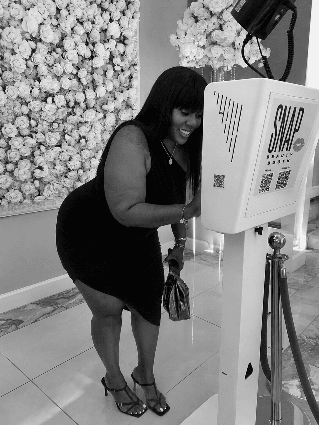 Guest enjoying the SnapJoy beauty booth in front of a white floral wall
