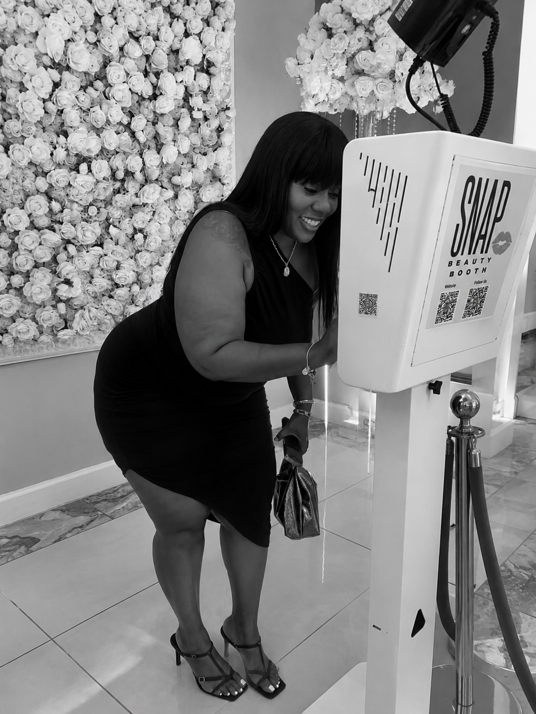 Guest enjoying the SnapJoy beauty booth in front of a white floral wall