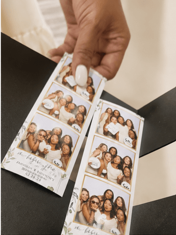 Guest holding wedding photo strips with greenery design
