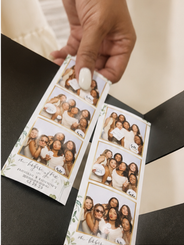 Guest holding wedding photo strips with greenery design