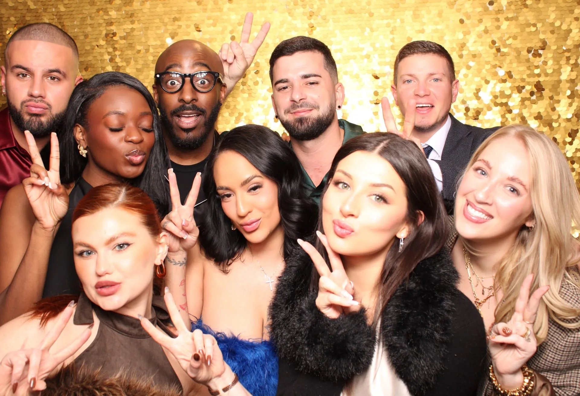 Large group photo with peace signs on gold sequin backdrop