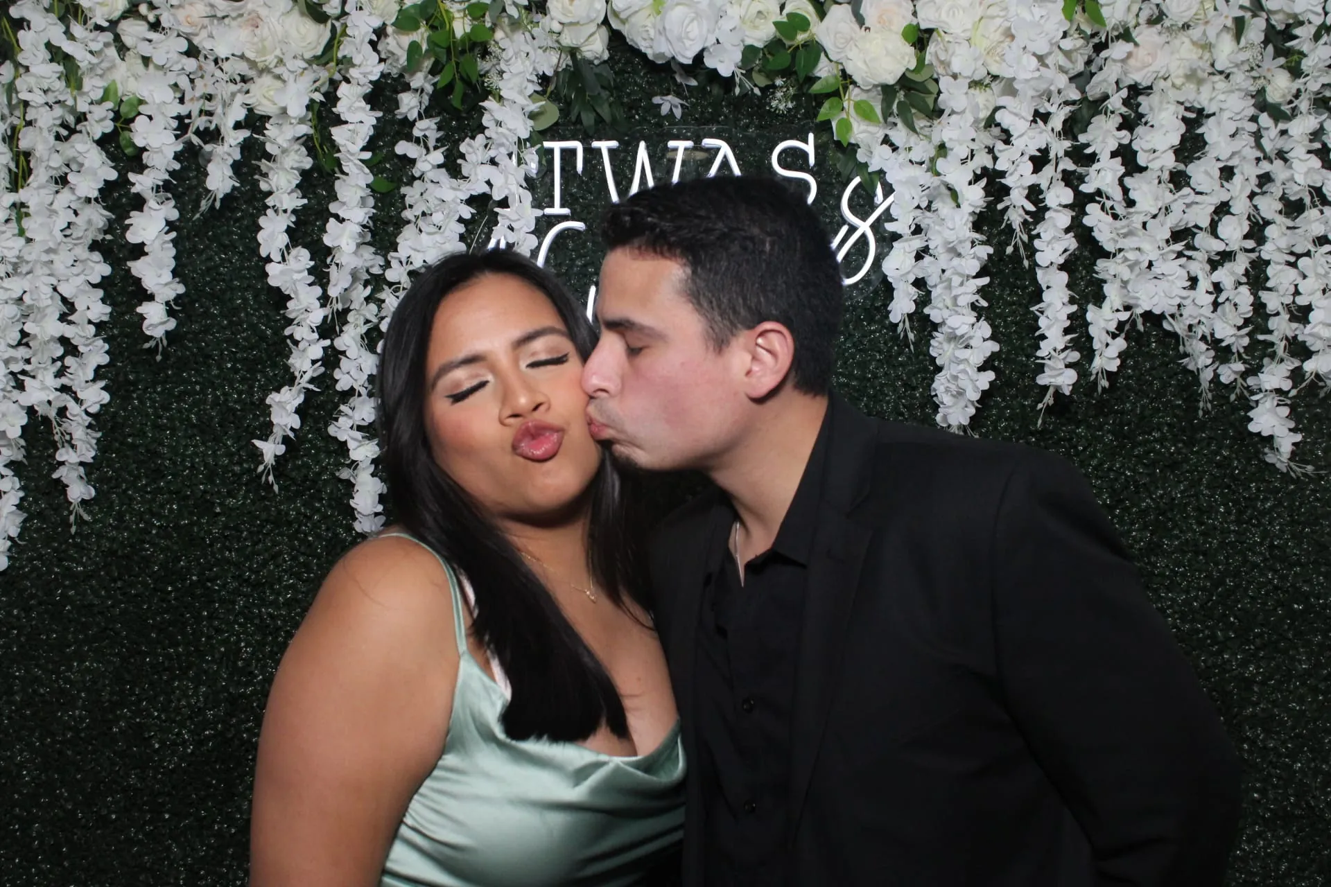 Couple posing in front of a lush floral wall
