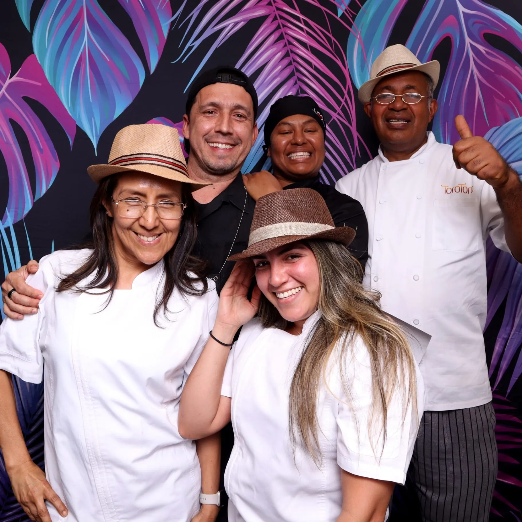 Chef team group portrait on neon palm backdrop