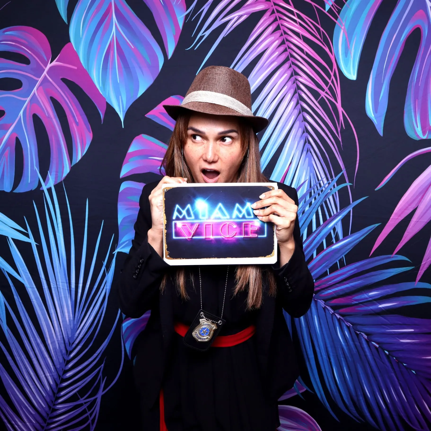 Woman holding Miami Vice sign with fedora hat